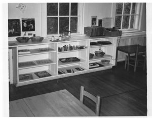 A photograph of educational materials stored on low shelves that are accessible to students.
